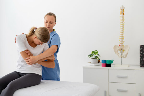 physiotherapist-helping-young-female-patient-her-clinic